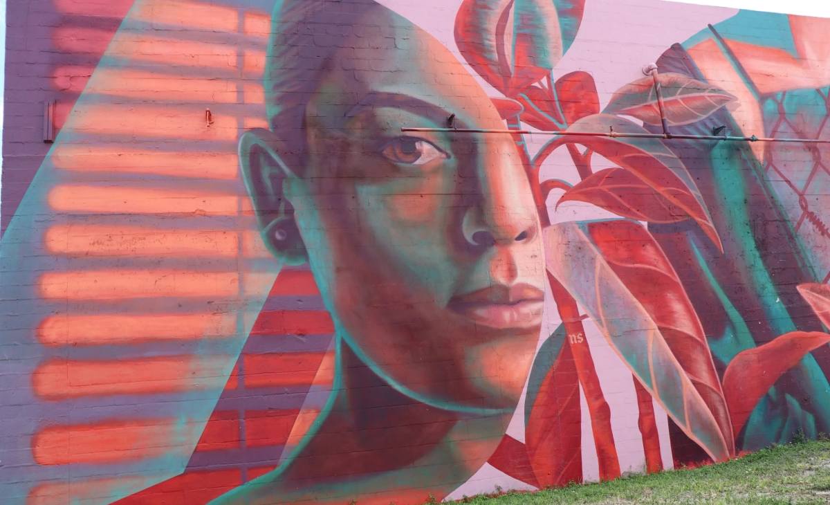 A mural of a woman 's face with plants in the background.