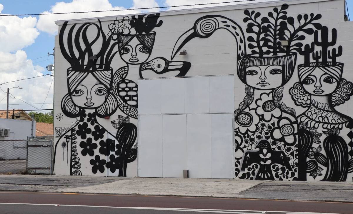 A mural of women with plants on the side of a building.