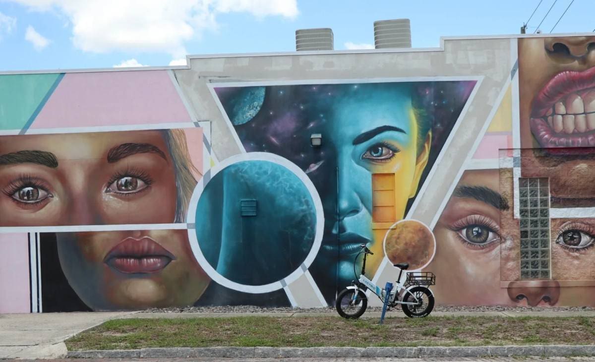 A man on a motorcycle in front of a mural.